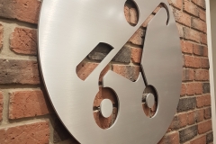 Custom solid brushed aluminium circular logo raised from the wall