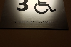 interior washroom sign with raised text and braille